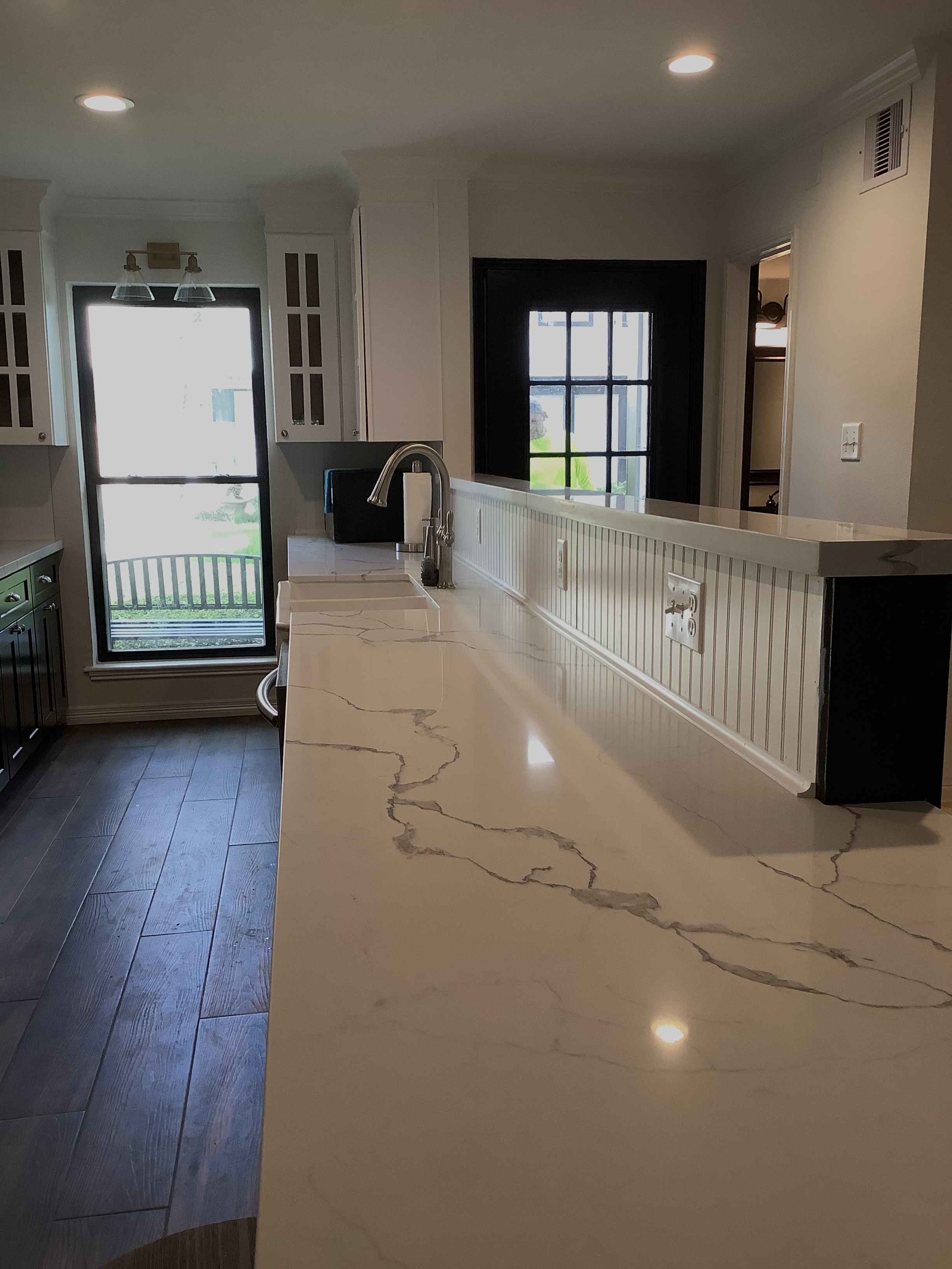 Bright kitchen counter with large window and wood floors