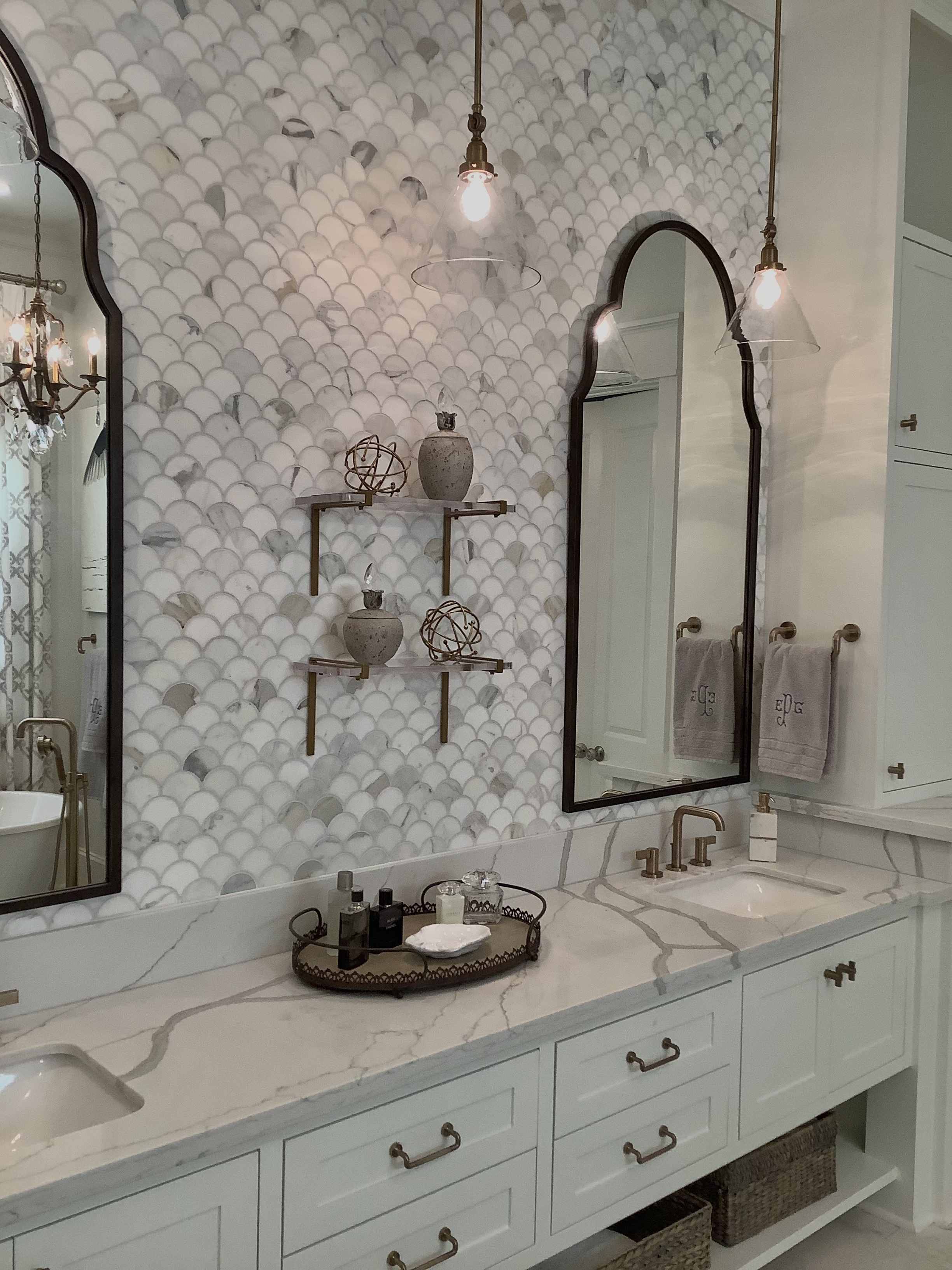 Bathroom with dual mirrors, scallop tile wall, and brass accents