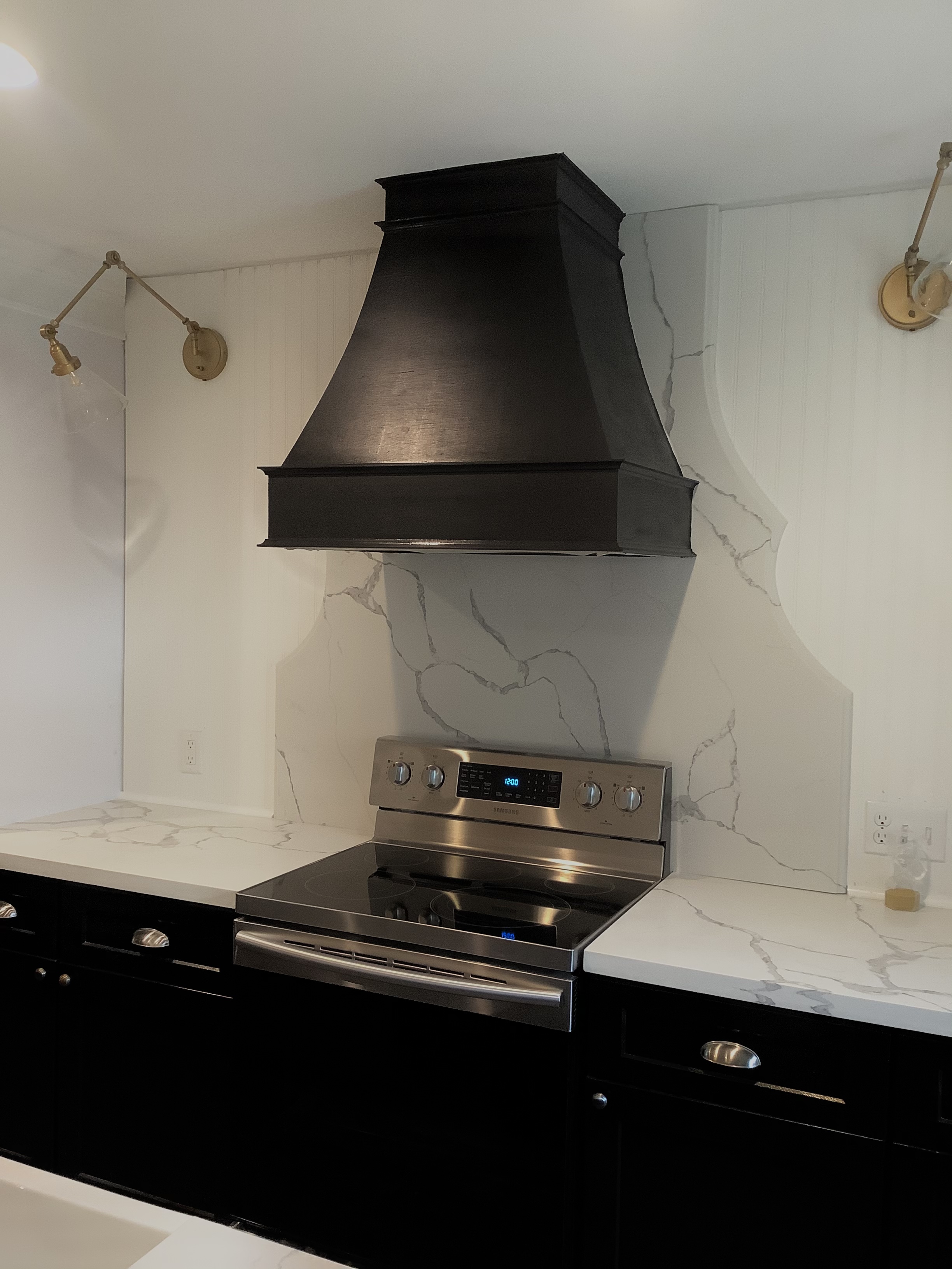 Black range hood over modern electric stove with white counters