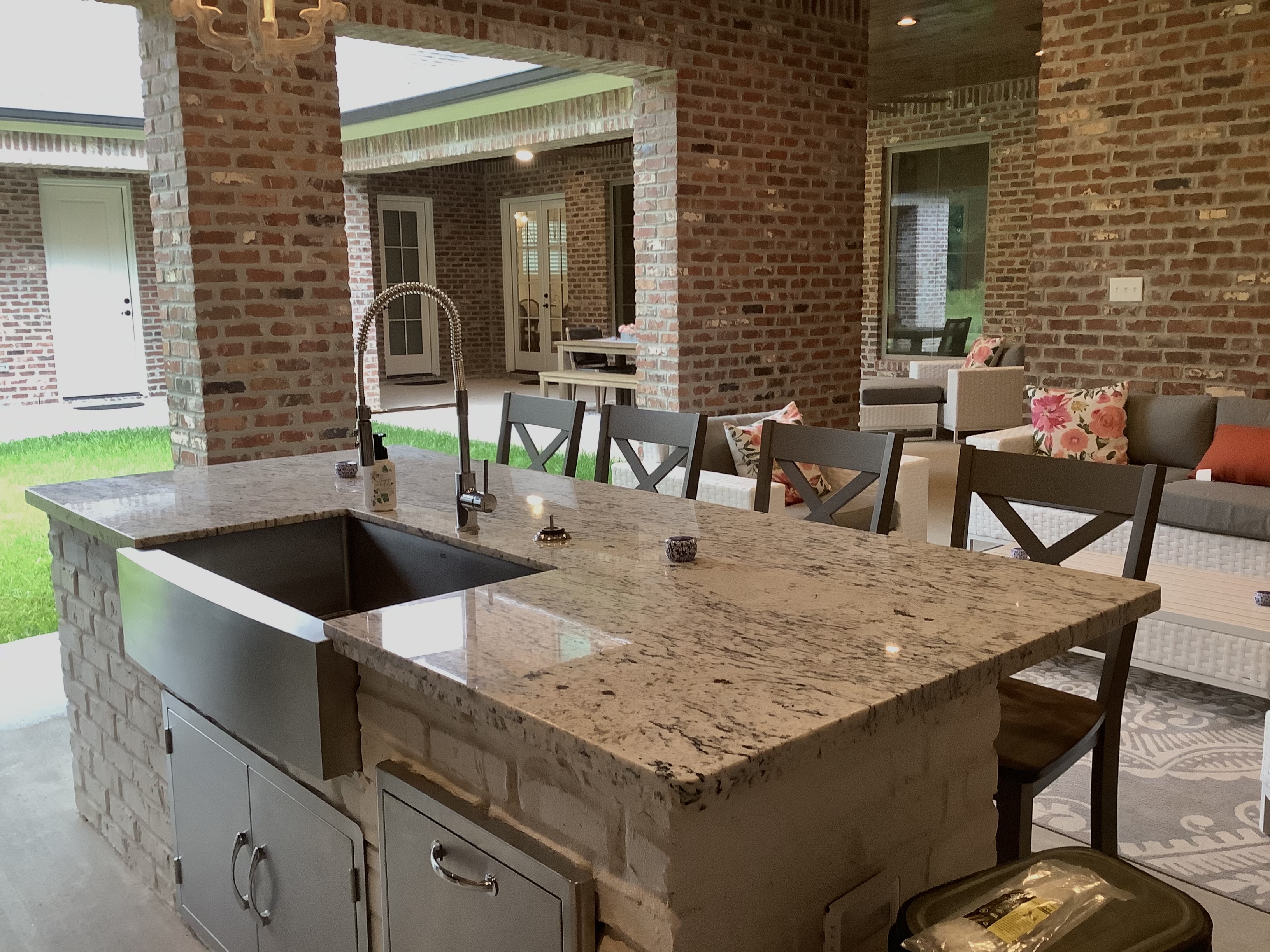 Outdoor kitchen with granite countertop and brick backdrop
