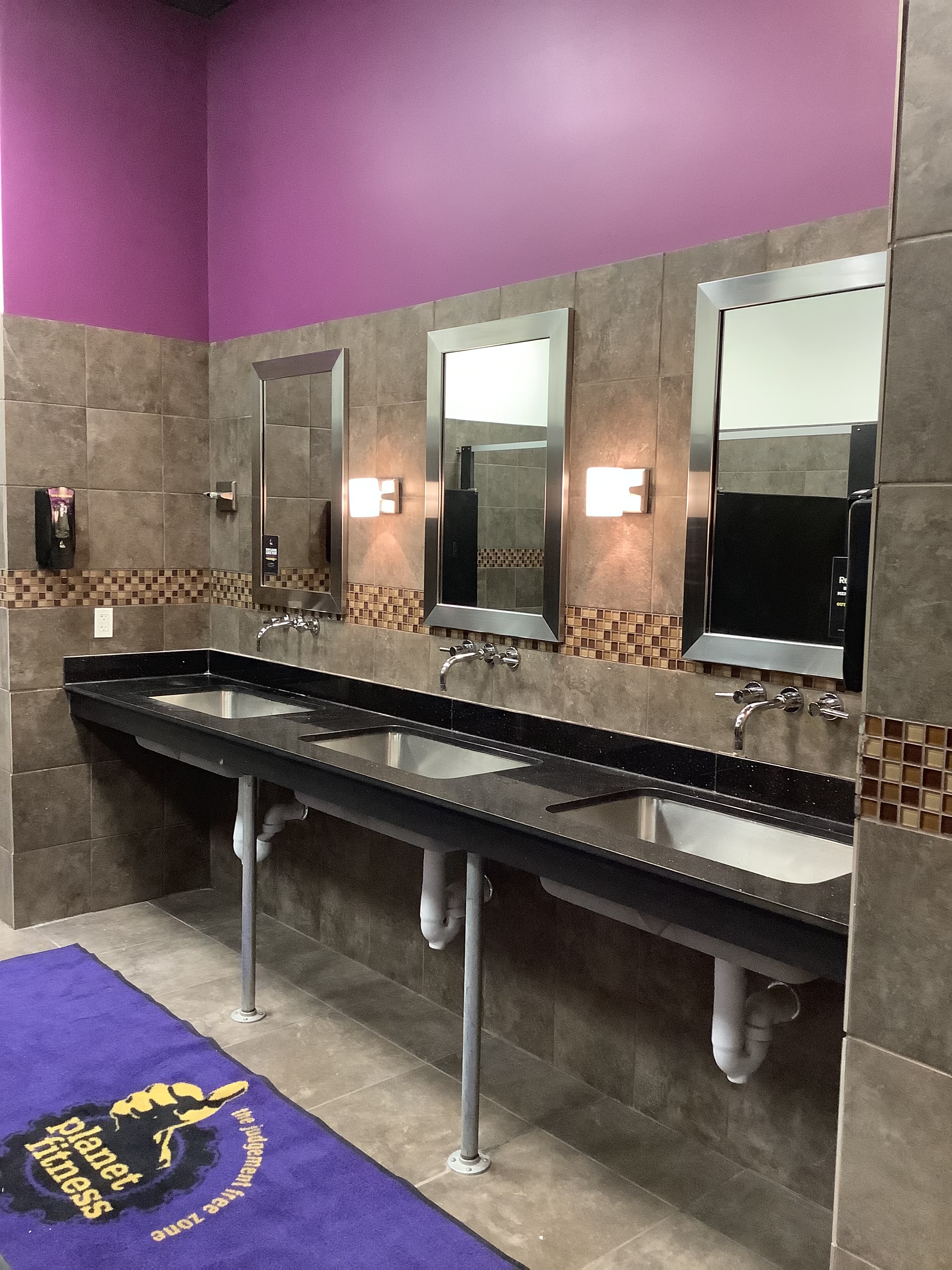 Gym restroom with purple walls and stainless fixtures